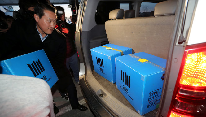 Một cán bộ điều tra truy tố đang chuyển các thùng chứa những chứng cứ thu giữ được tại một văn phòng chi nhánh của Quỹ hưu trí công của Hàn Quốc tại Jeonju, Hàn Quốc ngày 23-11 - Ảnh: Reuters