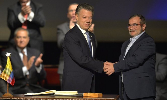 Tổng thống Juan Manuel Santos (trái) và ông Timochenko bắt tay nhau sau khi ký thỏa thuận hòa bình mới - Ảnh: AFP