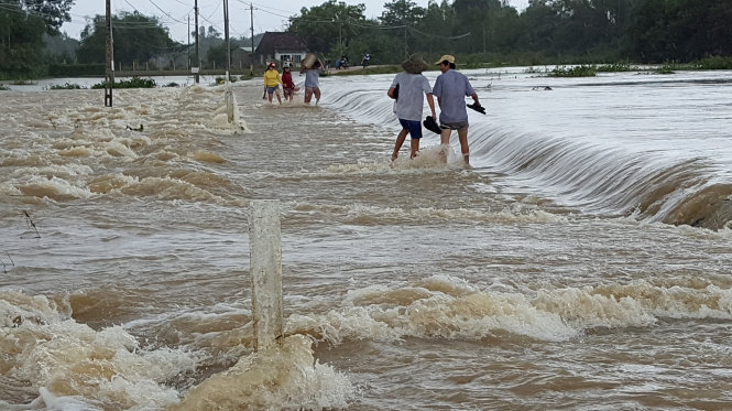 Để về nhà, nhiều người dân đã đánh liều băng qua dòng nước lũ chảy rất xiết. Ảnh chụp tại tràn Tân Thuận (xã Phước Thuận, huyện Tuy Phước) trưa 7-12 - Ảnh: Duy Thanh