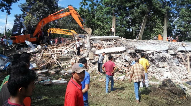 Lực lượng cứu hộ dùng máy móc hạng nặng để tìm kiếm những người sống sót dưới đống đổ nát ở huyện Pidie Jaya - Ảnh: AP
