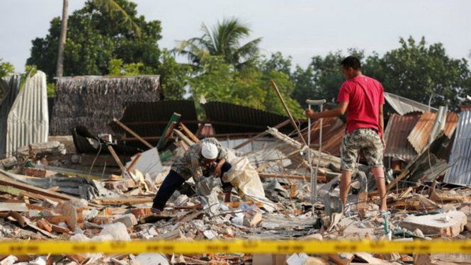 Người dân ở Pidie Jaya lượm lặt đồ đạc còn sót lại dưới đống đổ nát - Ảnh: REUTERS