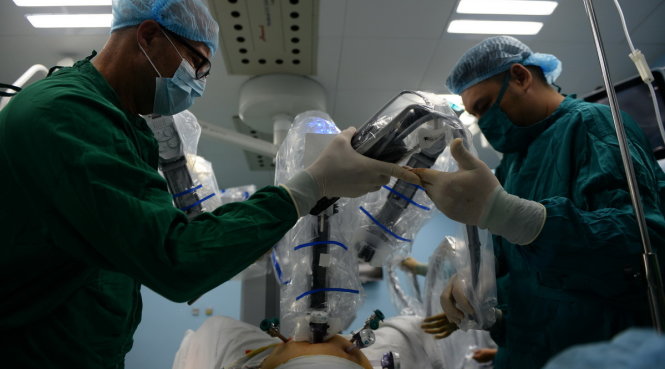 GS.Magnus (Thụy Điển) đưa cánh tay phẫu thuật robot tiến hành mổ cho bệnh nhân - Ảnh: Hữu Khoa