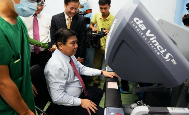 Chủ tịch UBND TP.HCM Nguyễn Thành Phong đang thử điều khiển robot phẫu thuật tại bệnh viện Bình Dân - Ảnh: Hữu Khoa