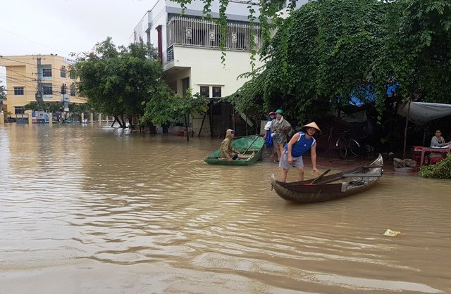 Đường ở trung tâm huyện lỵ Tuy Phước thành sông và người dân dùng thuyền để đi chợ - Ảnh: Xuân Vinh