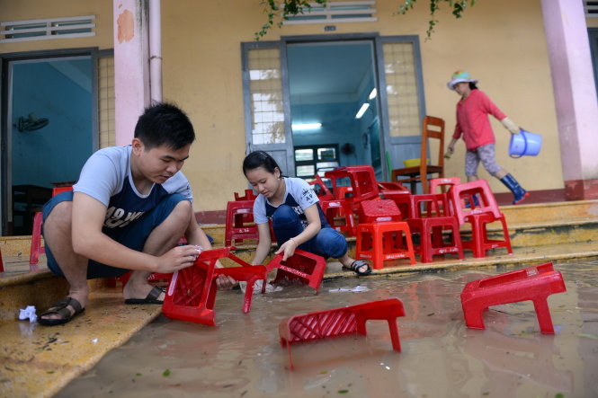 Học sinh Trường THPT số 1 Tuy Phước, (huyện Tuy Phước, tỉnh Bình Định) phụ thầy cô rửa ghế sau lũ - Ảnh: Hữu Khoa