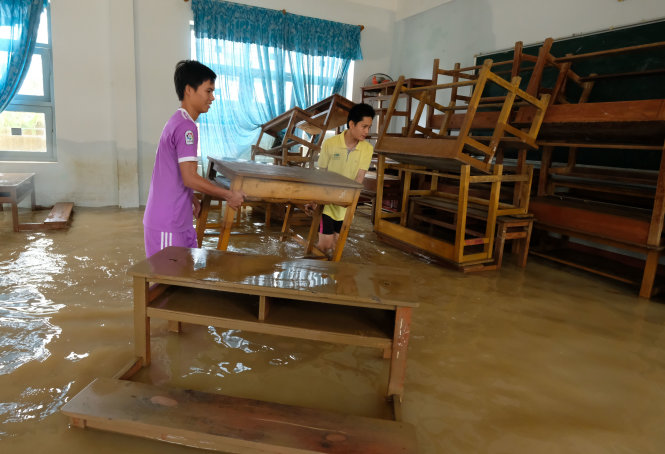 Thầy giáo đang lưu trú tại trường THPT Tuy Phước 3 (huyện Tuy Phước, tỉnh Bình Định) gom ghế bị nước lũ cuốn trôi - Ảnh: Mai Vinh