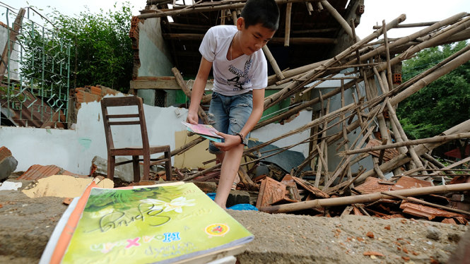 Em Đặng Nguyễn Tin (Trường THCS Phước Hoà, huyện Tuy Phước) lục tìm sách vở từ căn nhà đã sập - Ảnh: MAI VINH