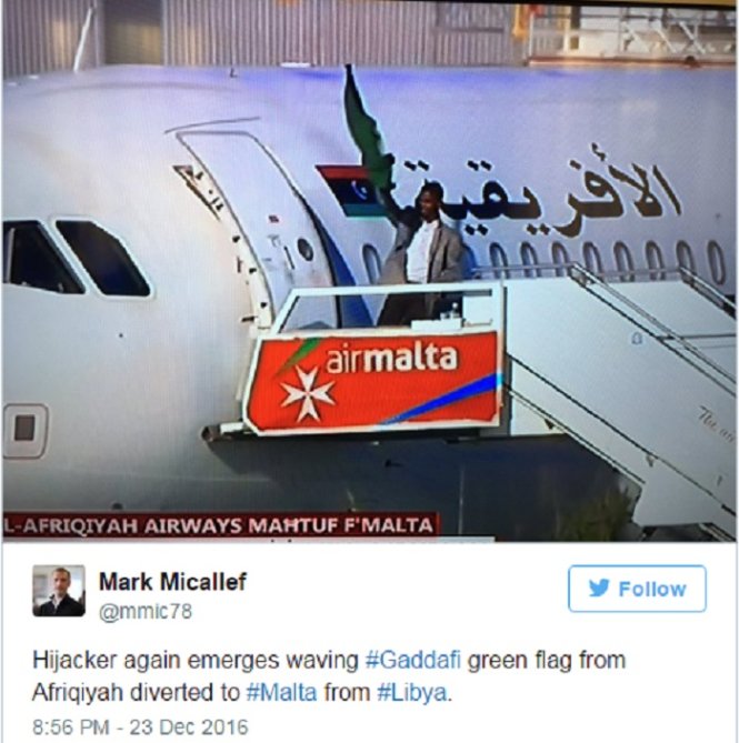 Hình ảnh chia sẻ trên mạng cho thấy một kẻ không tặc cầm cờ màu xanh của ông Gaddafi bên ngoài máy bay - Ảnh: RT/Twitter