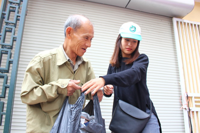 Một tình nguyện viên xúc động trước hoàn cảnh của ông Hồng, quê Hà Nam và đem tặng bọc quần áo ấm cho ông mà không lấy tiền - Ảnh: HÀ THANH