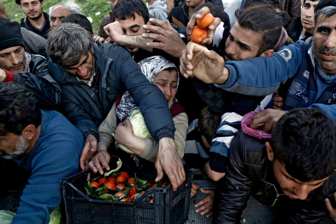 Thực phẩm được phân phát tại một trại tị nạn. Việc đóng cửa tuyến đường chính tới Đức khiến hơn 40.000 người di cư bị mắc kẹt tại Hi Lạp - Ảnh: EPA