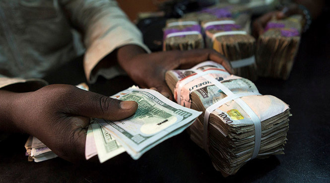 Thương nhân đổi tiền USD tại một cửa hàng đổi tiền ở Lagos, Nigeria - Ảnh: Reuters