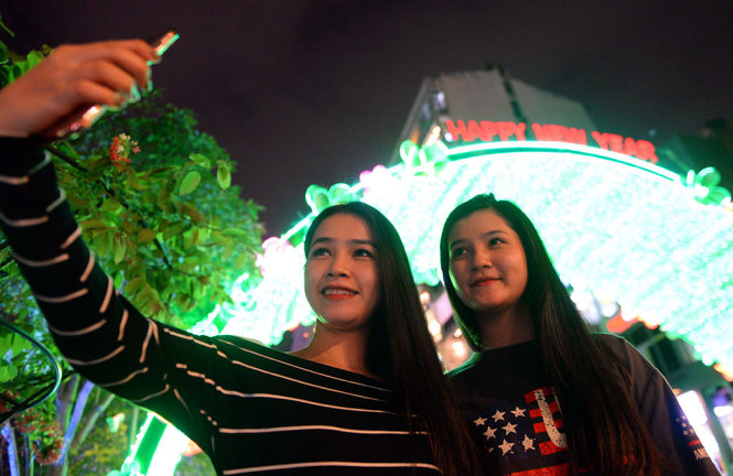 Hai bạn trẻ selfie trước dòng chữ Happy new year trên phố đi bộ Nguyễn Huệ - Ảnh: HỮU KHOA