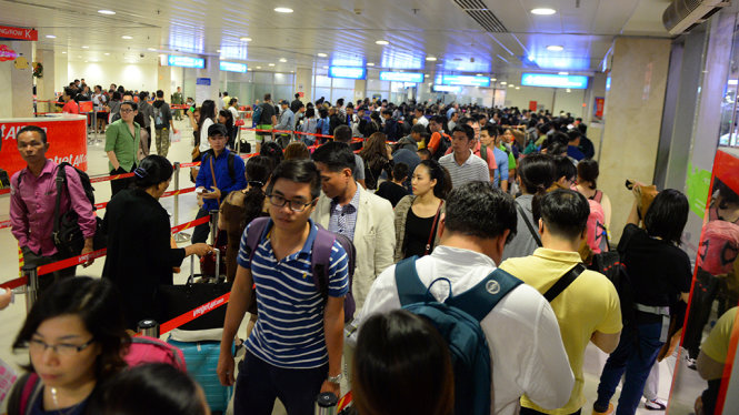 Hành khách xếp hàng dài chờ làm thủ tục lên máy bay tại sân bay Tân Sơn Nhất, TP.HCM - Ảnh: Hữu Khoa