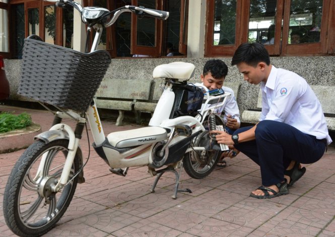 Hiếu (trái) và Khải lắp ráp thiết bị hạn chế tốc độ vào một xe đạp điện - Ảnh: TRẦN MAI