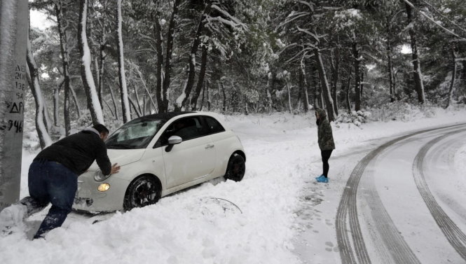 Một người đàn ông đẩy xe bị kẹt trong tuyết ở Malakasa, Hi Lạp - Ảnh: AP