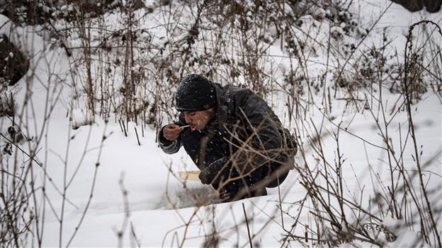 Một người tị nạn ăn trong tuyết ở Belgrade khi nhiệt độ giảm xuống -15 độ C - Ảnh: AFP