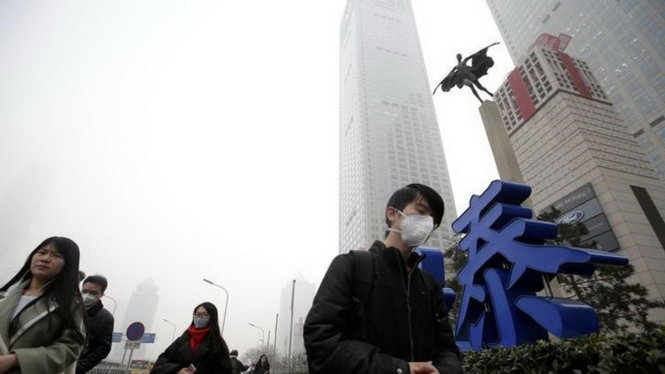 Người dân đeo khẩu trang đi trong sương mù ở quận trung tâm Bắc Kinh, Trung Quốc - Ảnh: Reuters