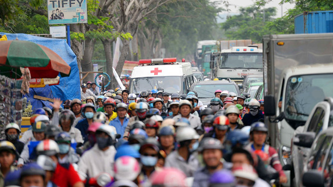 Một chiếc xe cấp cứu bất lực kêu vang giữa dòng xe kẹt cứng trên đường Nguyễn Văn Linh - Ảnh: HỮU KHOA