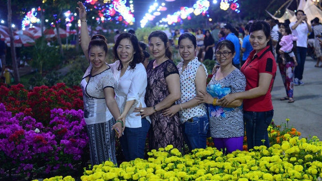 Người dân chụp ảnh kỷ niệm khi tham quan chợ hoa xuân Bình Điền 2017 tối 23-01 - Ảnh: QUANG ĐỊNH