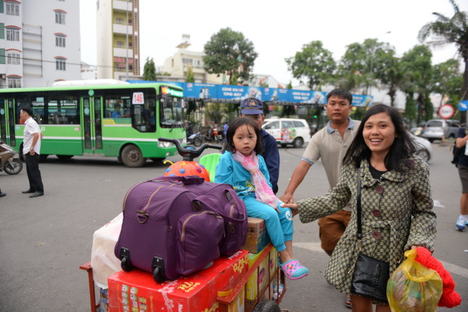 Gia đình chị Nguyễn Thị Nga (Quảng Ngãi) đẩy xe chở quần áo và quà tết về biếu người thân - Ảnh: HỮU KHOA