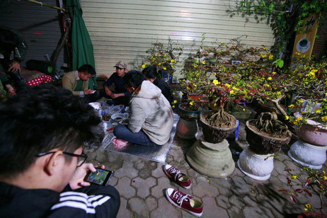 Một nhóm thanh niên vừa chơi điện tử vừa ăn đêm khi trông hàng - Ảnh: Nam Trần