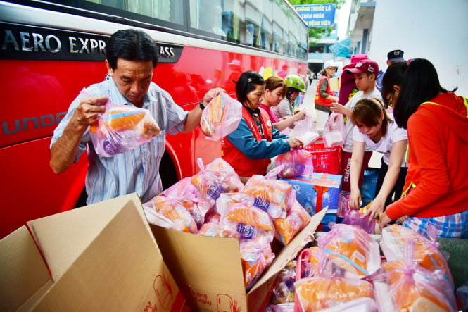 Những tình nguyện viên chuẩn bị những phần thức ăn trên xe cho bệnh nhân - Ảnh: HỮU THUẬN