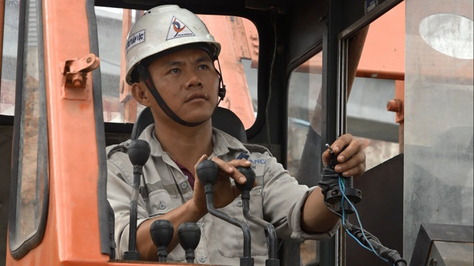 Anh Hà Việt – công nhân Công tu Cổ phần Đầu Tư và Xây dựng Tuấn Lộc đang chăm chú điều khiển máy móc trên công trường - Ảnh: CHẾ THÂN