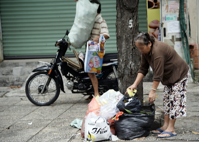 Một người dân ở khu Miếu Nổi (P.3, Q.Bình Thạnh, TP.HCM) đem rác ra đổ ở gốc cây - Ảnh: TỰ TRUNG