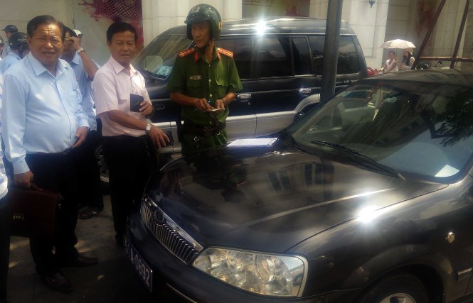 Ông Nguyễn Văn Thành (bìa trái), phó chủ tịch UBND Q.9 có mặt đề nghị lực lượng kiểm tra “bỏ qua” việc tài xế chở ông đậu xe trên lề đường nhưng không được giải quyết - Ảnh Q.Khải
