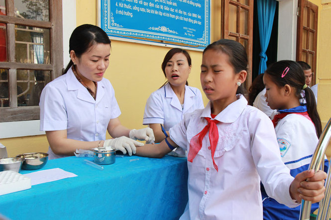Bác sĩ lấy mẫu máu cho học sinh Trường tiểu học - THCS Hạnh Dịch, huyện Quế Phong (Nghệ An) để xét nghiệm về bệnh viêm cầu thận cấp - Ảnh: LÀI HỒ