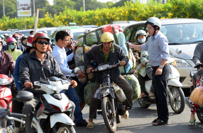 Để giảm kẹt xe nhiều người đi xe máy nhanh chóng phụ người đàn ông ngã xe lên - Ảnh: Hữu Khoa