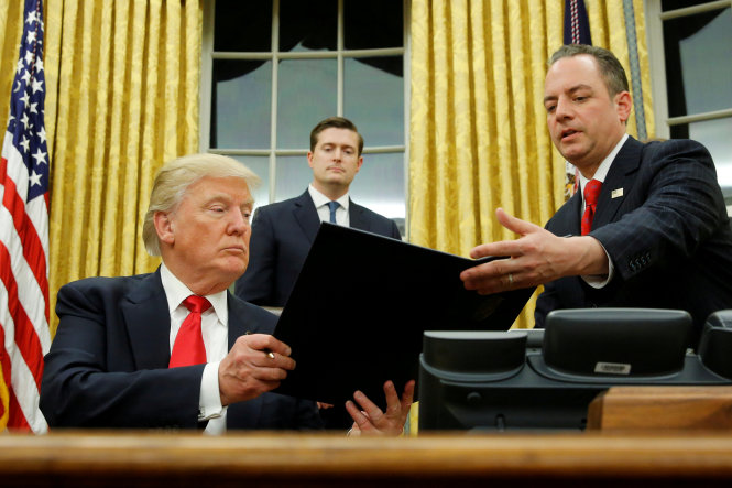 Ông Trump trao cho ông Priebus sắc lệnh hành pháp chỉ đạo các cơ quan chính phủ giảm bớt gánh nặng của chính sách Obamacare tại phòng Bầu dục, Nhà Trắng ngày 20-1 (ảnh tư liệu) - Ảnh: Reuters