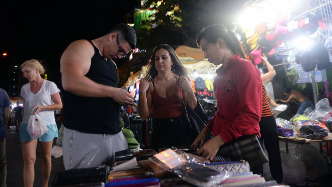 Du khách nước ngoài chọn mua đồ lưu niệm tại chợ đêm Bến Thành - Ảnh: Hữu Khoa
