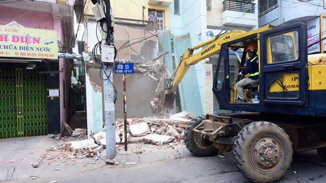 Máy múc kéo sập tường trụ sở khu phố lấn chiếm vỉa hè - Ảnh: Hữu Thuận