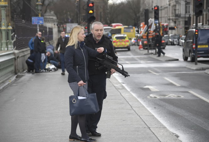Cảnh sát Anh hướng dẫn một phụ nữ rời khu vực đến nơi an toàn - Ảnh: Reuters
