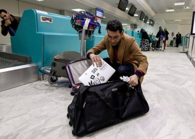 Một hành khách Libya cất laptop vào hành lý trước khi bay đến London tại Sân bay Quốc tế Tunis-Carthage hôm 25-3 - Ảnh: AFP