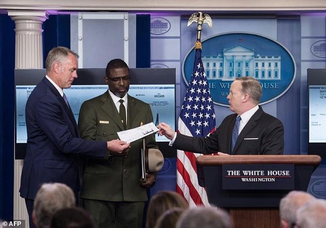 Phát ngôn viên Nhà Trắng Sean Spicer (phải) trao cho Bộ trưởng Nội vụ Ryan Zinke tấm séc quyên góp tiền lương quý đầu của tổng thống Donald Trump - Ảnh: AFP