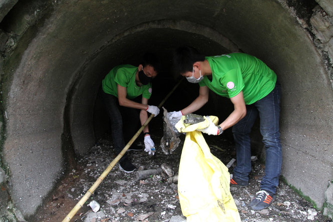 Các sinh viên nam dọn rác trong những cống nước đổ ra sông - Ảnh: Phương Chinh