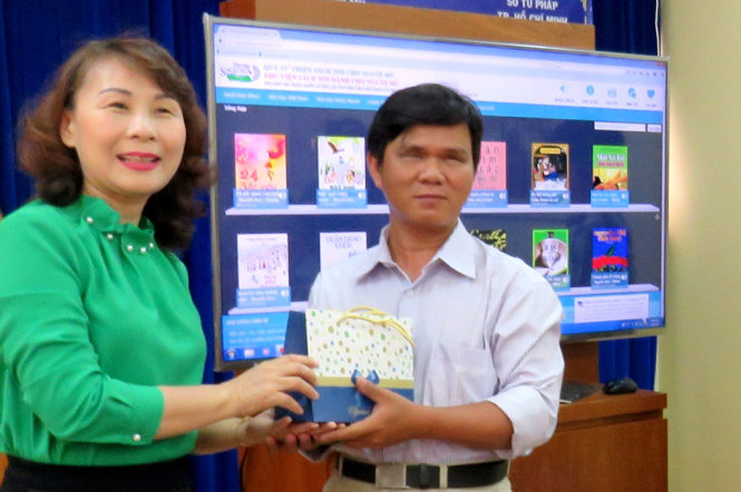 Bà Lê Thị Bình Minh trao đĩa CD cho ông Nguyễn Văn Ca-ủy viên thường vụ Hội người mù TP HCM - Ảnh: ÁI NHÂN