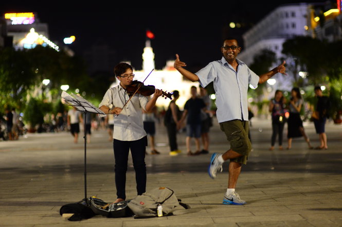 Khách du lịch Brazil nhảy theo tiếng đàn violon trên phố đi bộ Nguyễn Huệ, TP.HCM - Ảnh: QUANG ĐỊNH