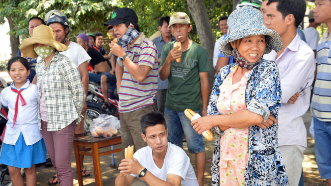 Người dân mua bánh mỳ ăn và túc trực chặn xe - Ảnh: Thanh Ba