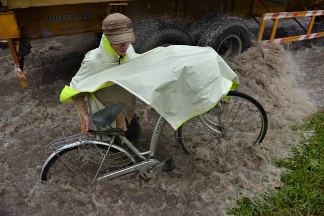 Một người đi xe đạp bị kẹt giữa dòng nước - Ảnh: Lê Phan