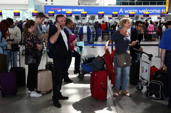 Hành khách xếp hàng chờ với hành lý trên tay tại các quầy kiểm tra của hãng hàng không British Airways ở sân bay Heathrow ngày 28-5 - Ảnh: Reuters