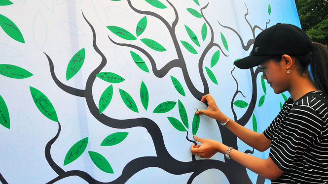 Một nữ sinh ký cam kết và dán lên cây cam kết bảo vệ môi trường tại ngày hội - Ảnh: A LỘC