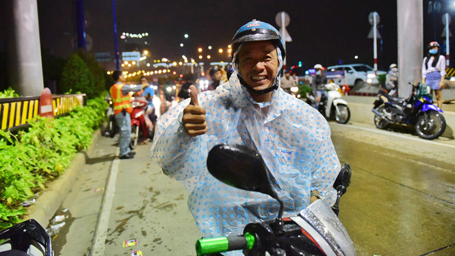 Anh Trương Văn Huân cảm kích khi được CSGT hỗ trợ áo mưa - Ảnh: HỮU THUẬN