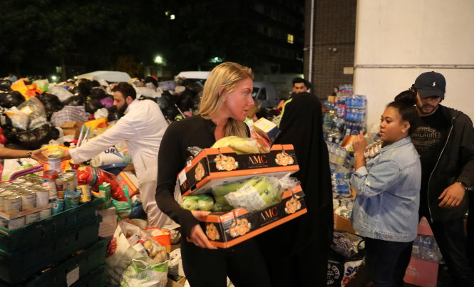 Nhiều người tình nguyện, trong ngày 15-6, đã đến hỗ trợ công tác cứu trợ thực phẩm và nước uống cho các nạn nhân vụ cháy - Ảnh: Reuters