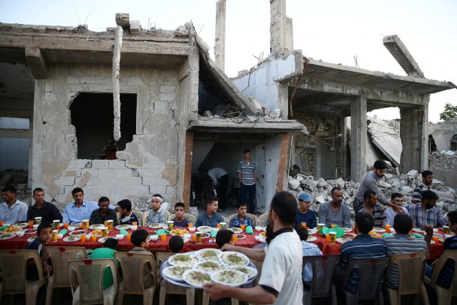 Người dân Syria ở thị trấn Douma thuộc ngoại ô thủ đô Damascus ăn sáng trong lễ chay Ramadan giữa cảnh hoang tàn vào ngày 18-6 - Ảnh: Reuters