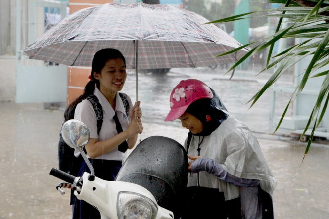Học sinh trường THPT Phú Nhuận Q.Phú Nhuận, TP.HCM được phụ huynh đón về trong trời mưa tầm tã sau khi làm hồ sơ dự thi - Ảnh: Thu Trang