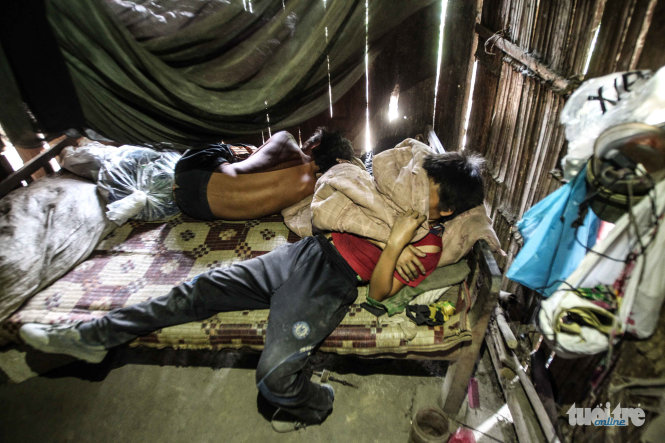 Không kịp cởi quần áo, cậu bé Lý Mí Toàn 11 tuổi lao ngày vào giường để ngủ bù sau một buổi sáng mót quặng mệt mỏi - Ảnh: NGUYỄN KHÁNH
