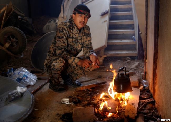 Một chiến binh thuộc lực lượng SDF đang ở trong một ngôi nhà tại Raqqa, Syria - Ảnh: Reuters